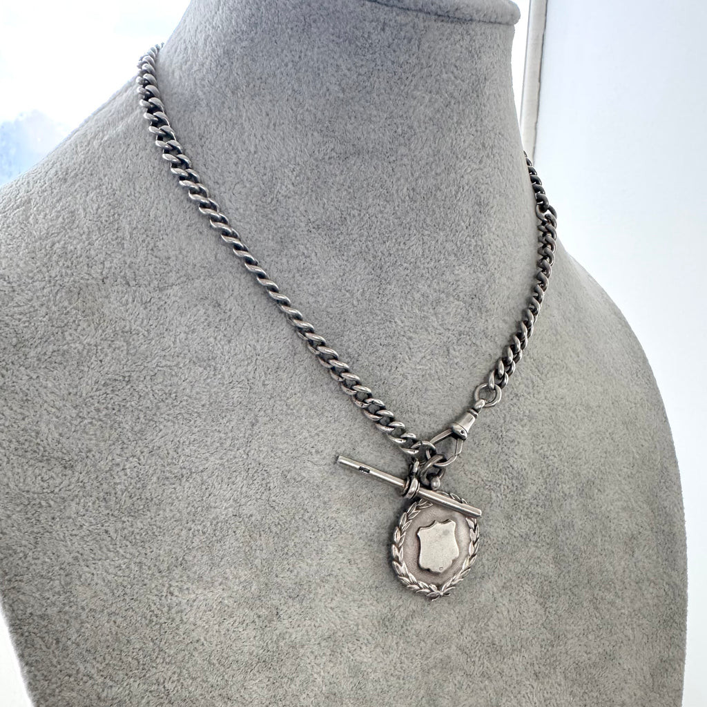 Silver chain necklace with a pendant on a gray mannequin bust