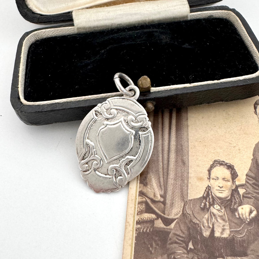 Vintage 1957 silver watch fob on an old jewellery box and photo