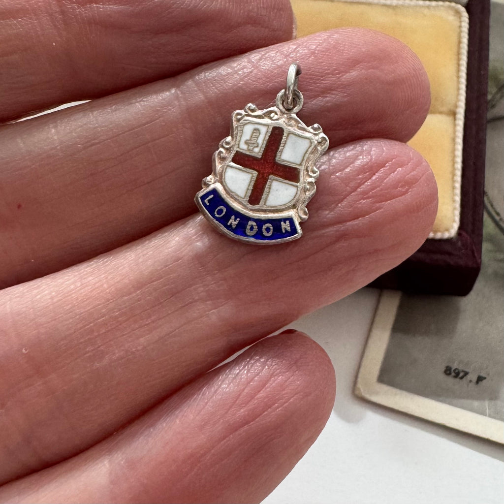 Vintage London silver coat of arms charm in a womans hand.