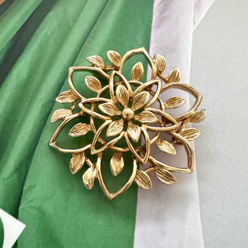 Vintage 1962 Sarah Coventry 'Peta-Lure' gold openwork flower brooch (Rare GB Mark) on a green fabric background