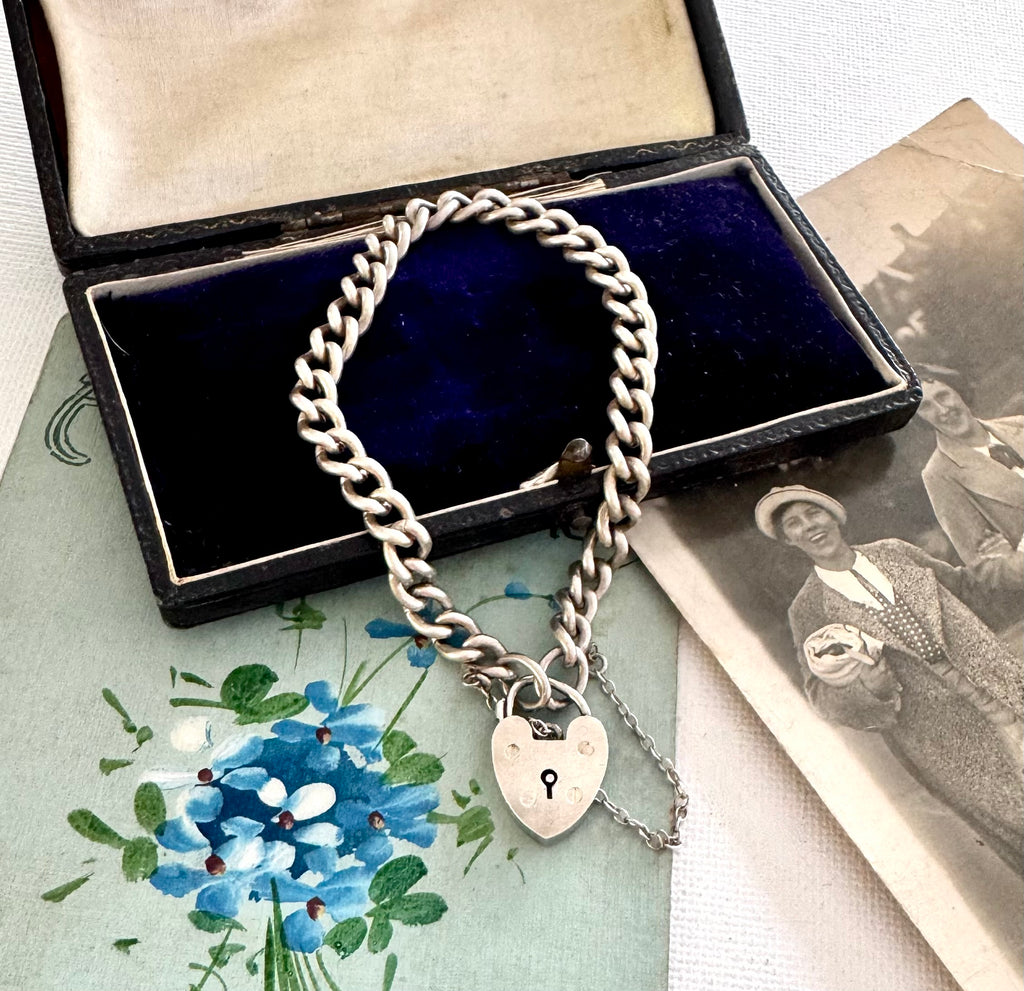 Silver chain bracelet with a heart-shaped lock charm in an open jewelry box.