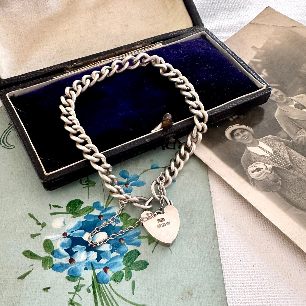 Silver chain bracelet with a heart-shaped clasp on a floral card and vintage photo