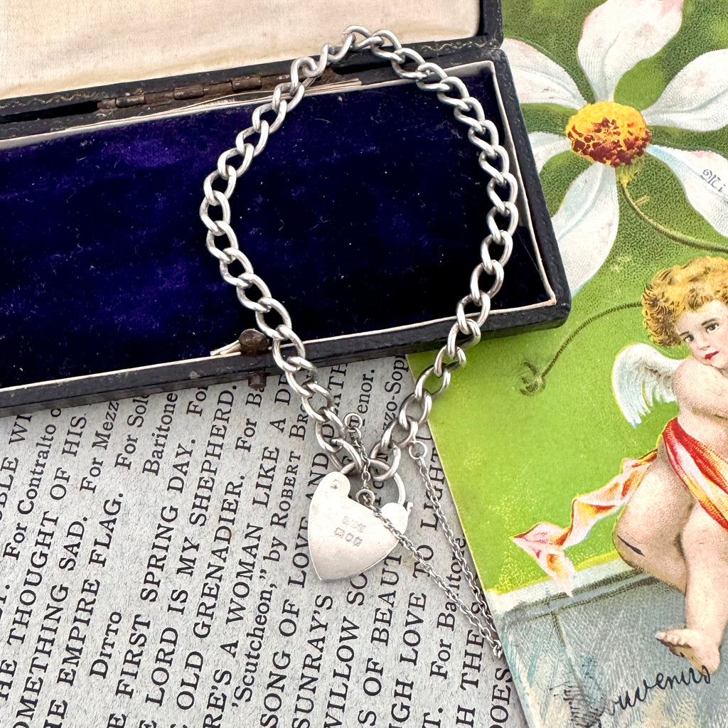 Silver bracelet with heart charm on a vintage book page with cherub illustration