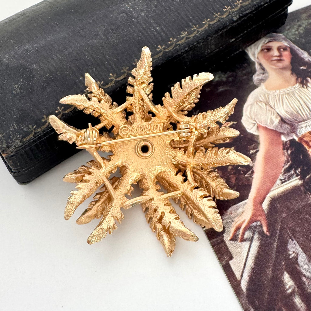 Vintage 1968 Sarah Coventry Cosmopolitan sunflower brooch on an old jewellery box and with an old postcard