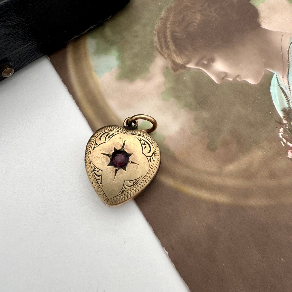 Vintage 9ct gold lined heart locket with gemstone on an old postcard