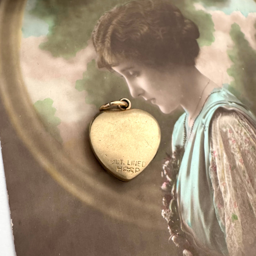 Vintage 9ct gold lined heart locket with gemstone on an old postcard