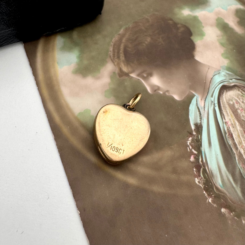 Gold heart-shaped locket with '109C' engraving on a vintage-style background