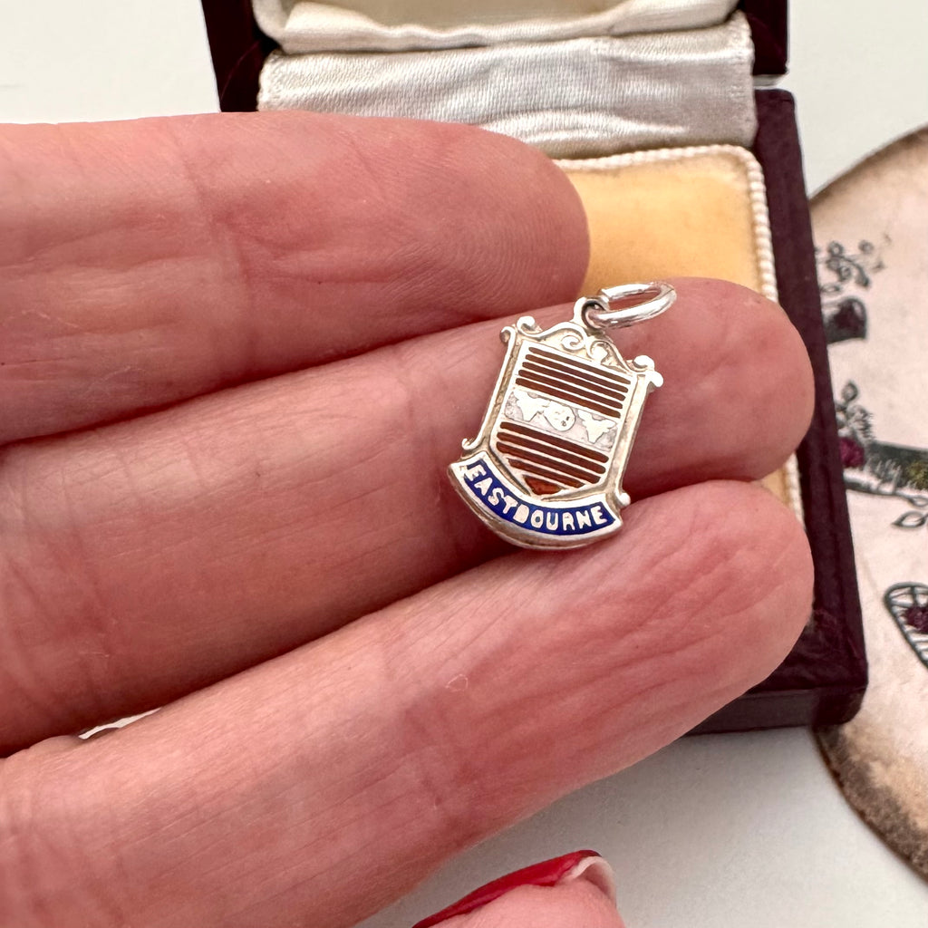 Vintage silver Eastbourne travel charm on a jewellery box and in a woman's hand