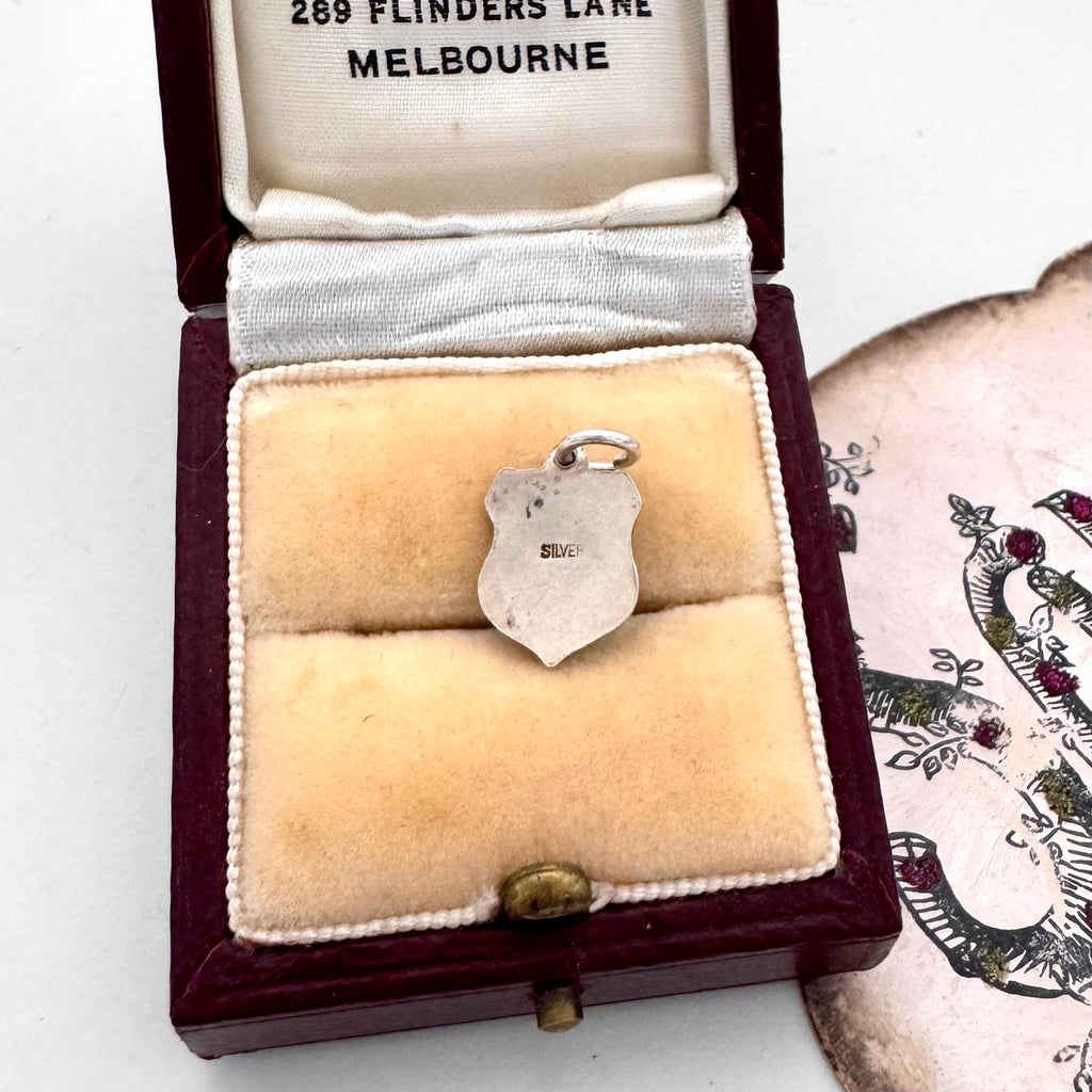 Jewelry box with a vintage silver charm featuring a coat of arms and 'MACKENZIE' text on a white background.