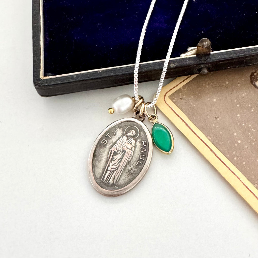 Vintage St Paul silver pendant, green gemstone, and pearl necklace on a white surface.