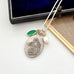Neckalce with religious pendant, green stone, pearl, and gold accents on a white background