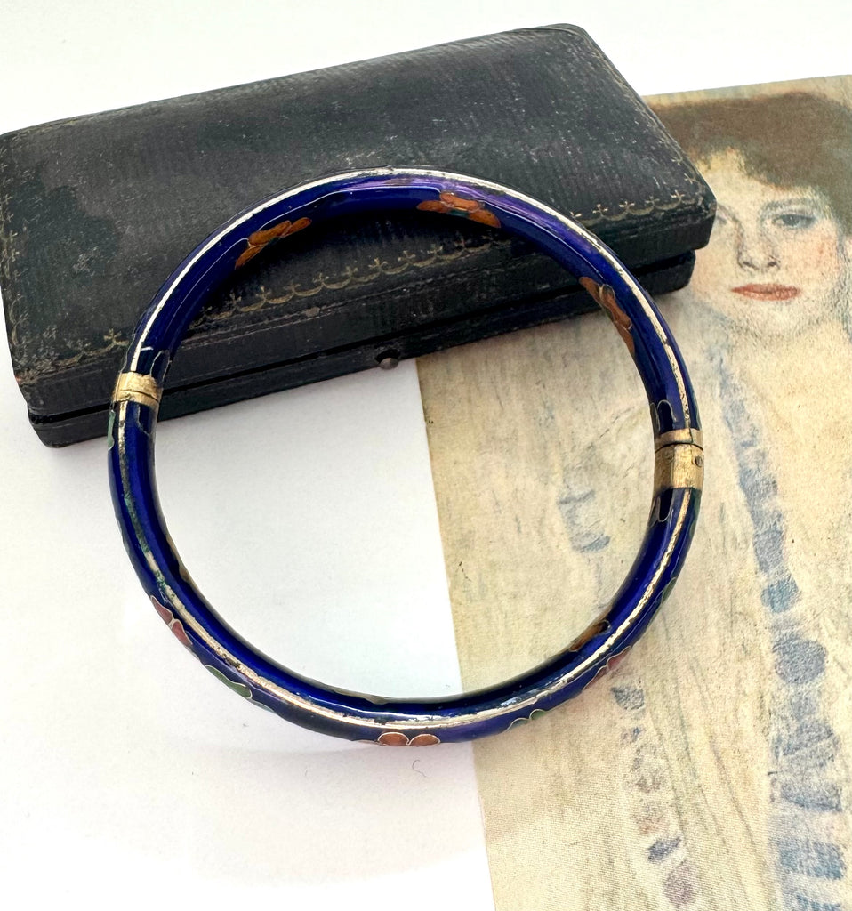 Blue cloisonne bangle with gold accents on a white background