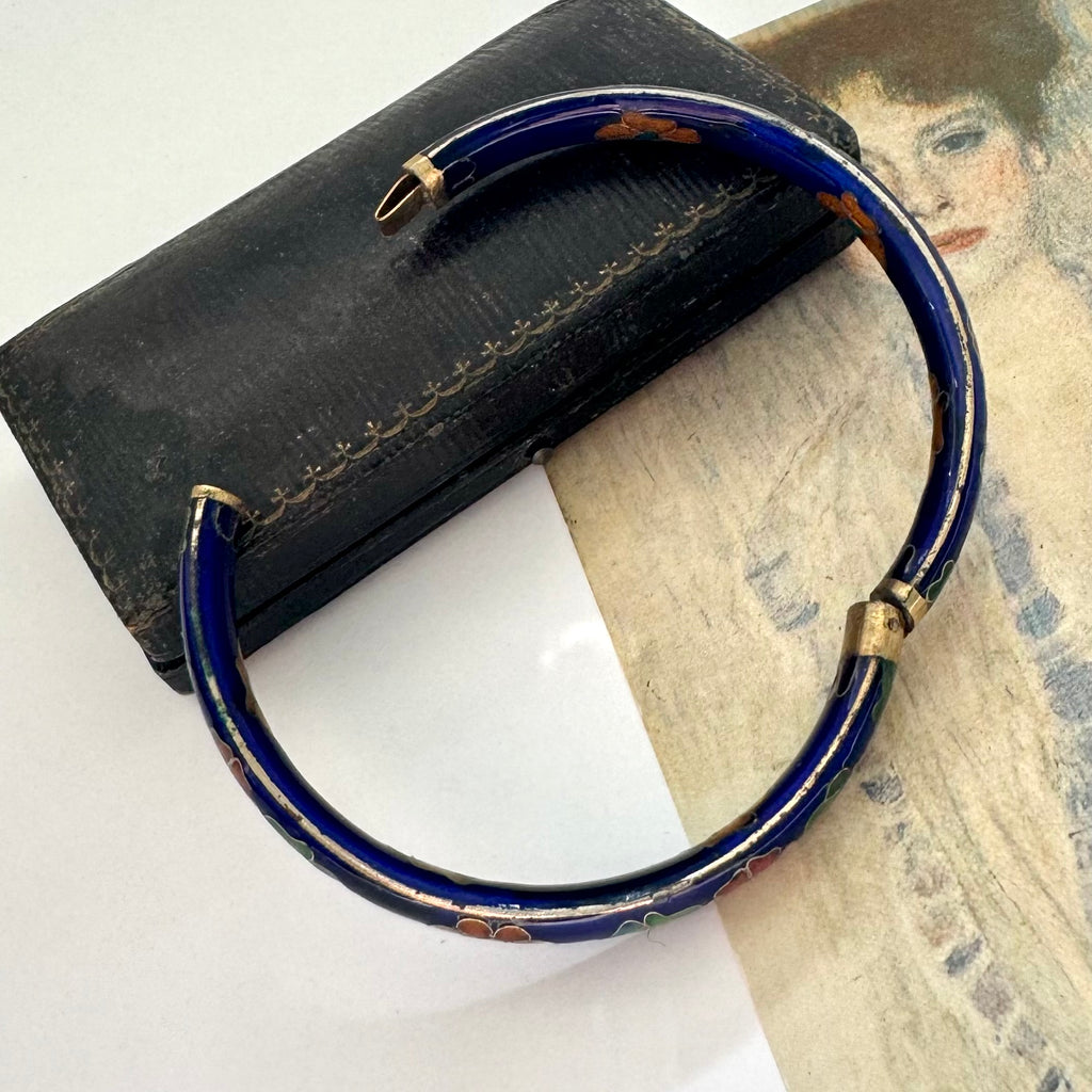 Blue cloisonne bracelet with gold accents on a textured surface