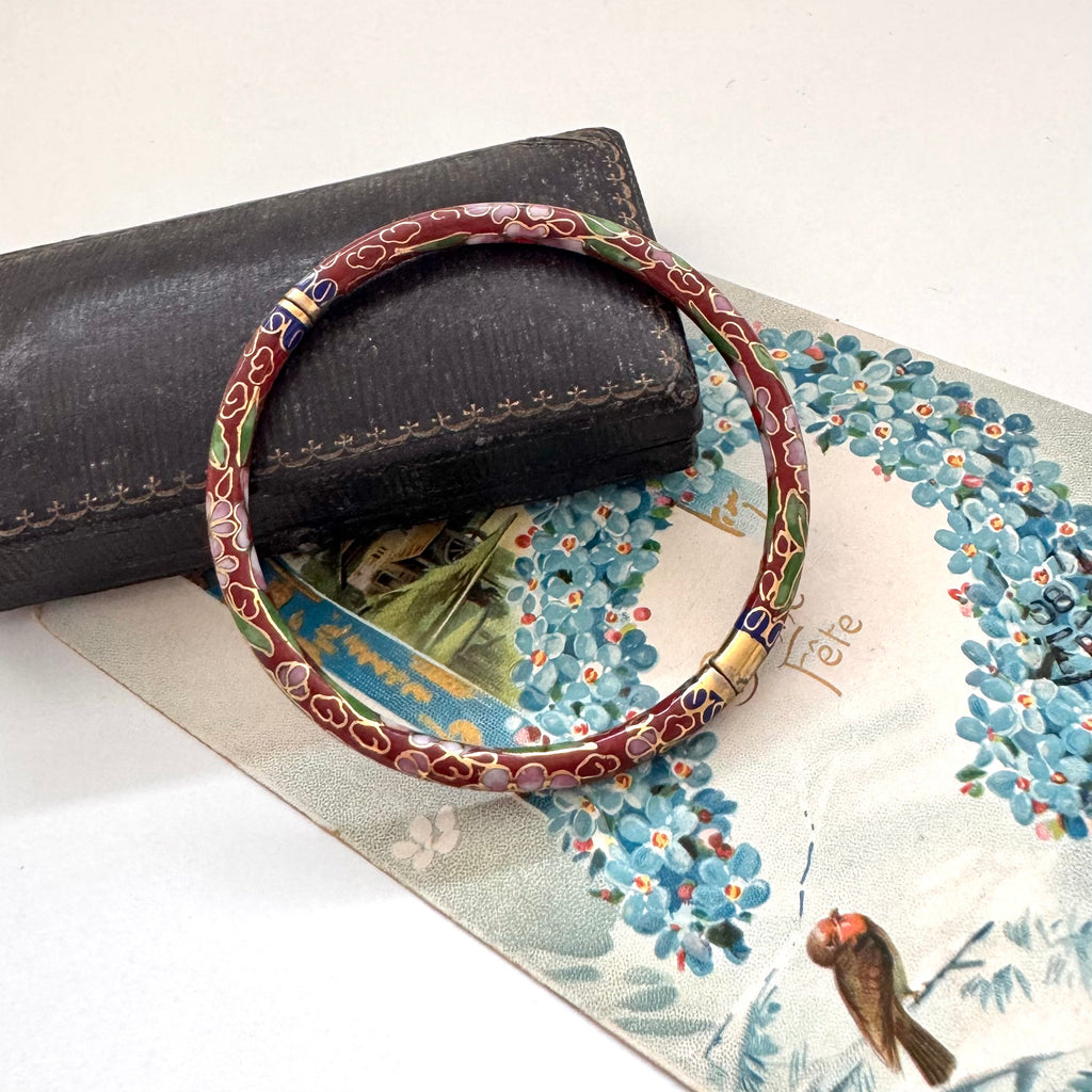 Vintage brown cloisonne bangle on an old jewellery box and vintage Christmas postcard.