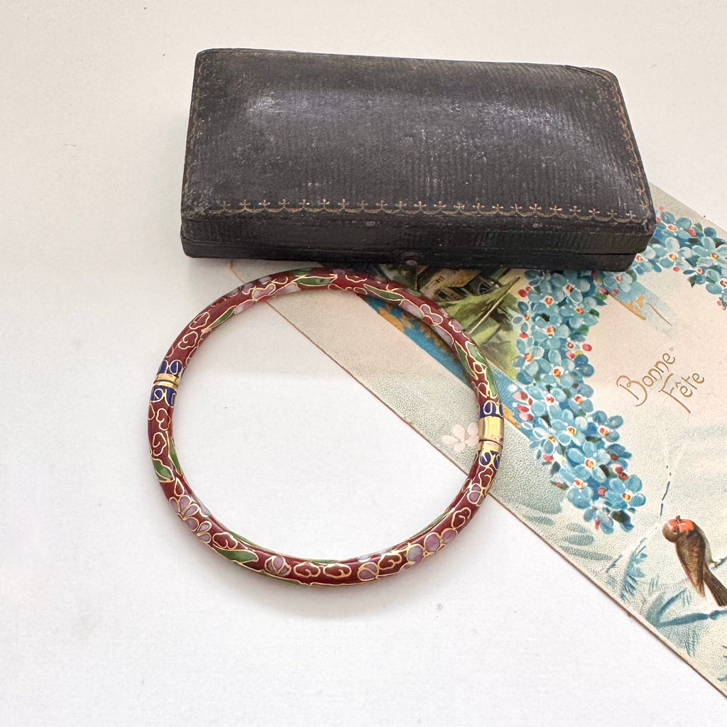 Vintage brown cloisonne bangle on an old jewellery box and vintage Christmas postcard.