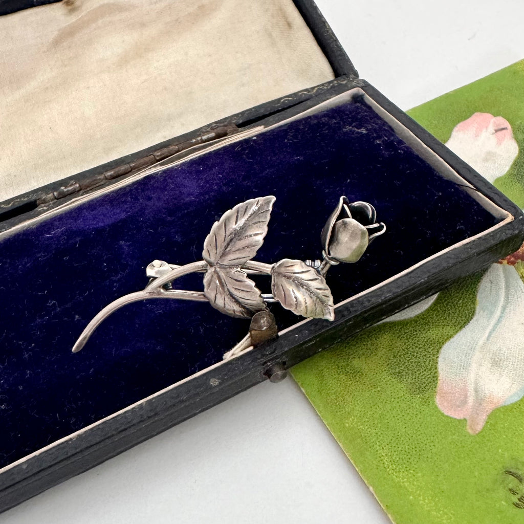 Vintage Danish John Lauritzen silver leaf and rose brooch on a textured black surface