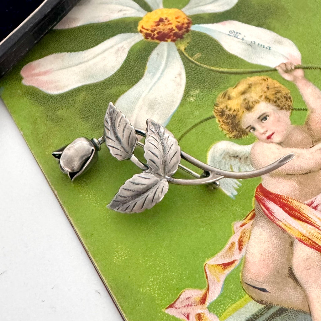 Vintage Danish silver brooch with floral design on a vintage-style card featuring a cherub and flowers.