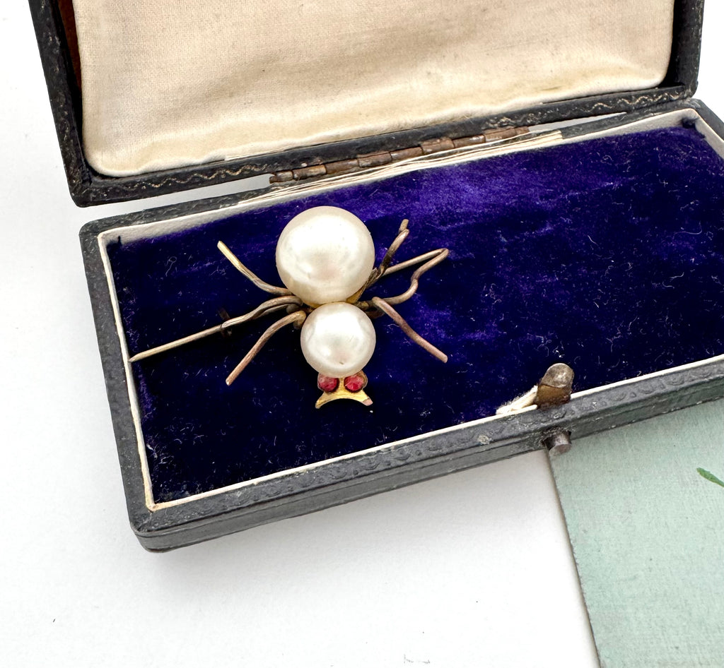 Pearl spider brooch in an open jewelry box on a white background