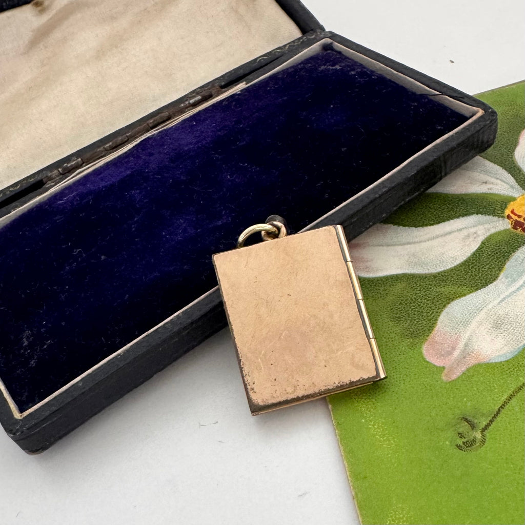 Vintage 12ct gold fill book locket in a jewelry box on a floral-patterned surface