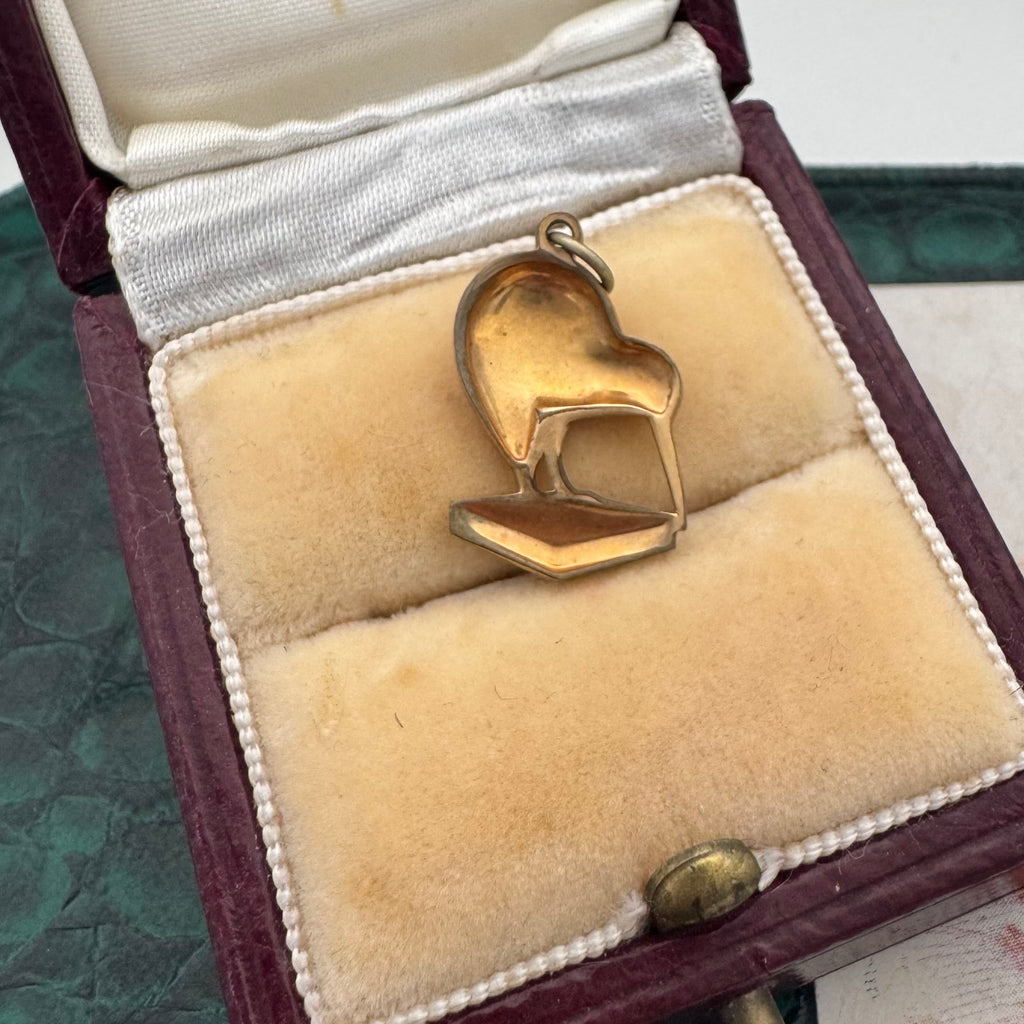 Gold kiwi bird pendant in a jewelry box with a textured surface.
