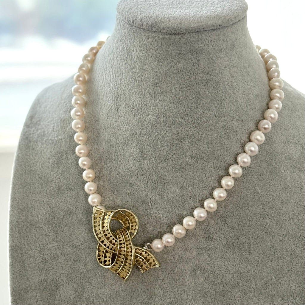 Pearl necklace with a gold pendant on a gray bust