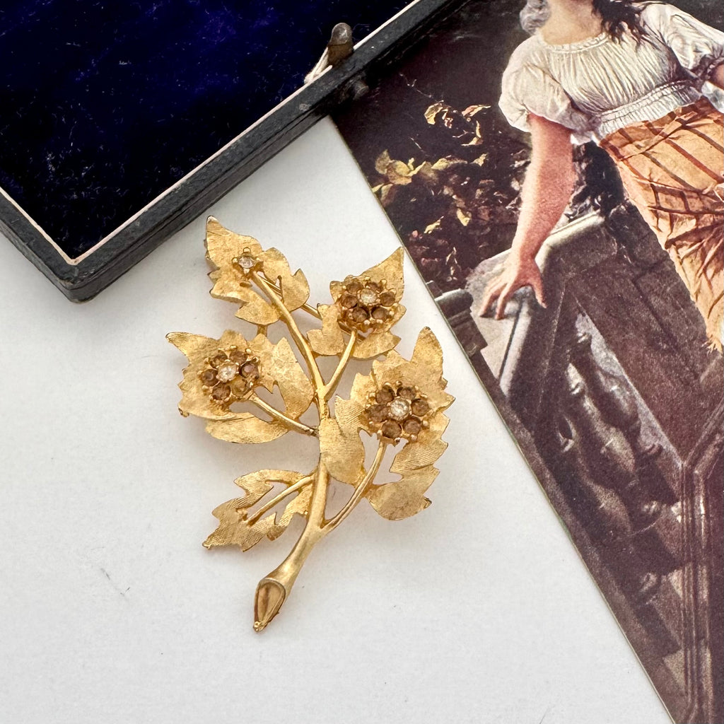 Gold floral brooch on a white surface with an old photograph in the background