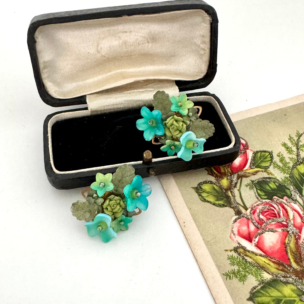 Vintage floral earrings in a black jewelry box with a botanical illustration in the background