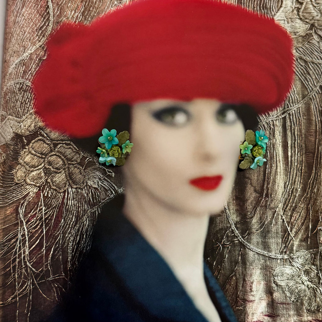 Artistic depiction of a woman wearing a red hat and earrings against a textured background