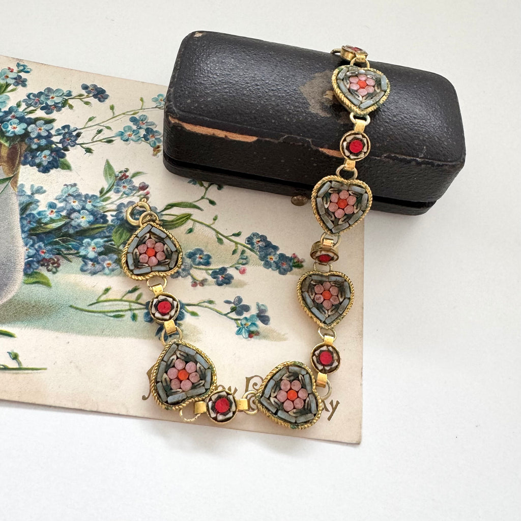 Vintage micro mosaic bracelet with floral designs in a jewelry box on a floral vintage postcard.