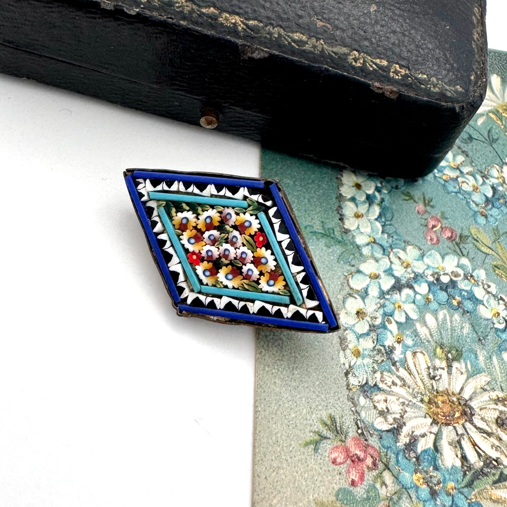 Vintage micro mosaic brooch on a floral-patterned fabric background