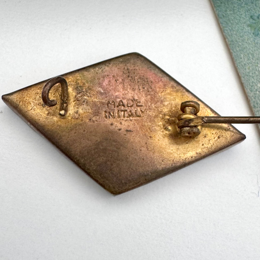 Back of vintage micro mosaic brooch on a floral-patterned fabric background
