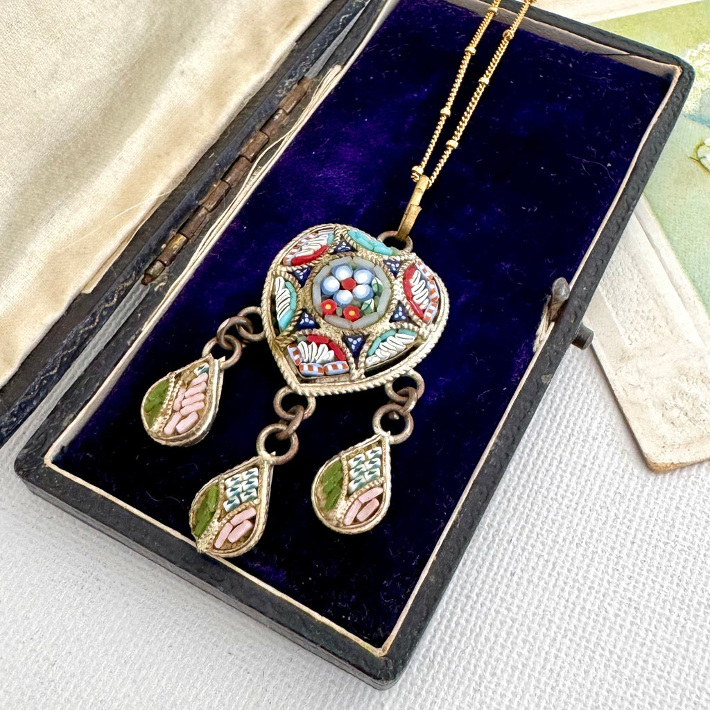 A vintage gold-tone micro mosaic pendant necklace with matching drop earrings, featuring colorful enamel inlay, displayed inside an open dark velvet jewelry box.