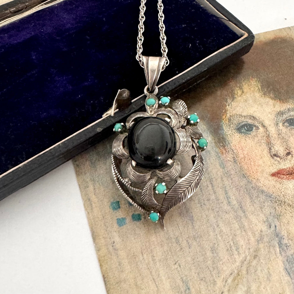 Vintage art nouveau mid century revival necklace with black stone and turquoise stones on a textured surface