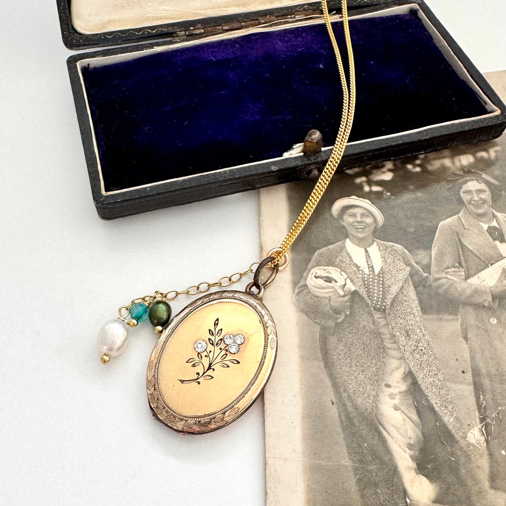 Vintage gold locket with floral design on a white surface next to an old photograph