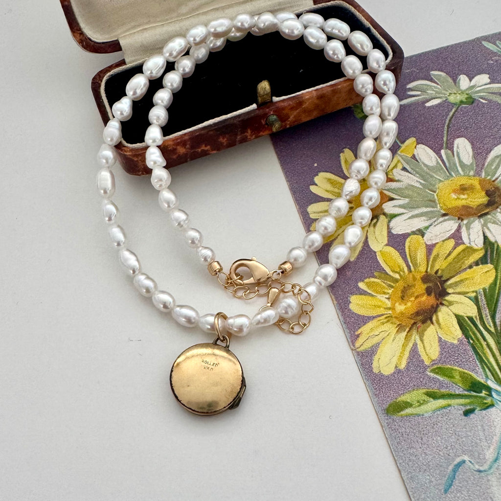 Vintage rolled gold locket and pearl necklace on a vintage postcard and jewellery box