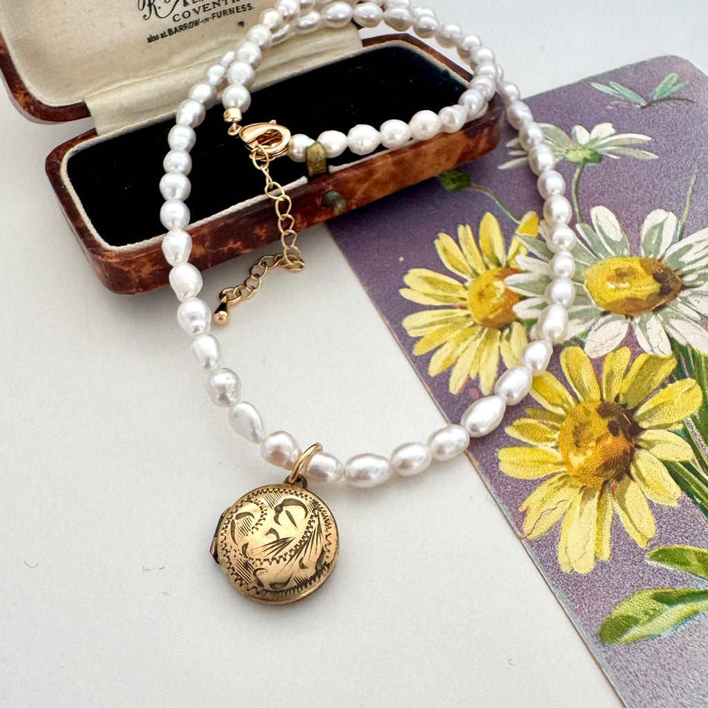 Vintage rolled gold locket and pearl necklace on a vintage postcard and jewellery box