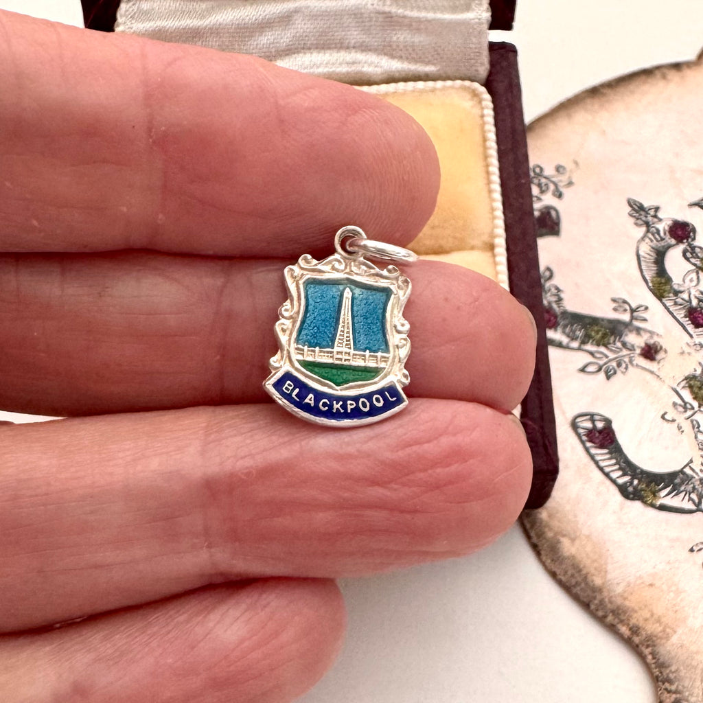 Vintage silver charm with 'Blackpool' text held between fingers