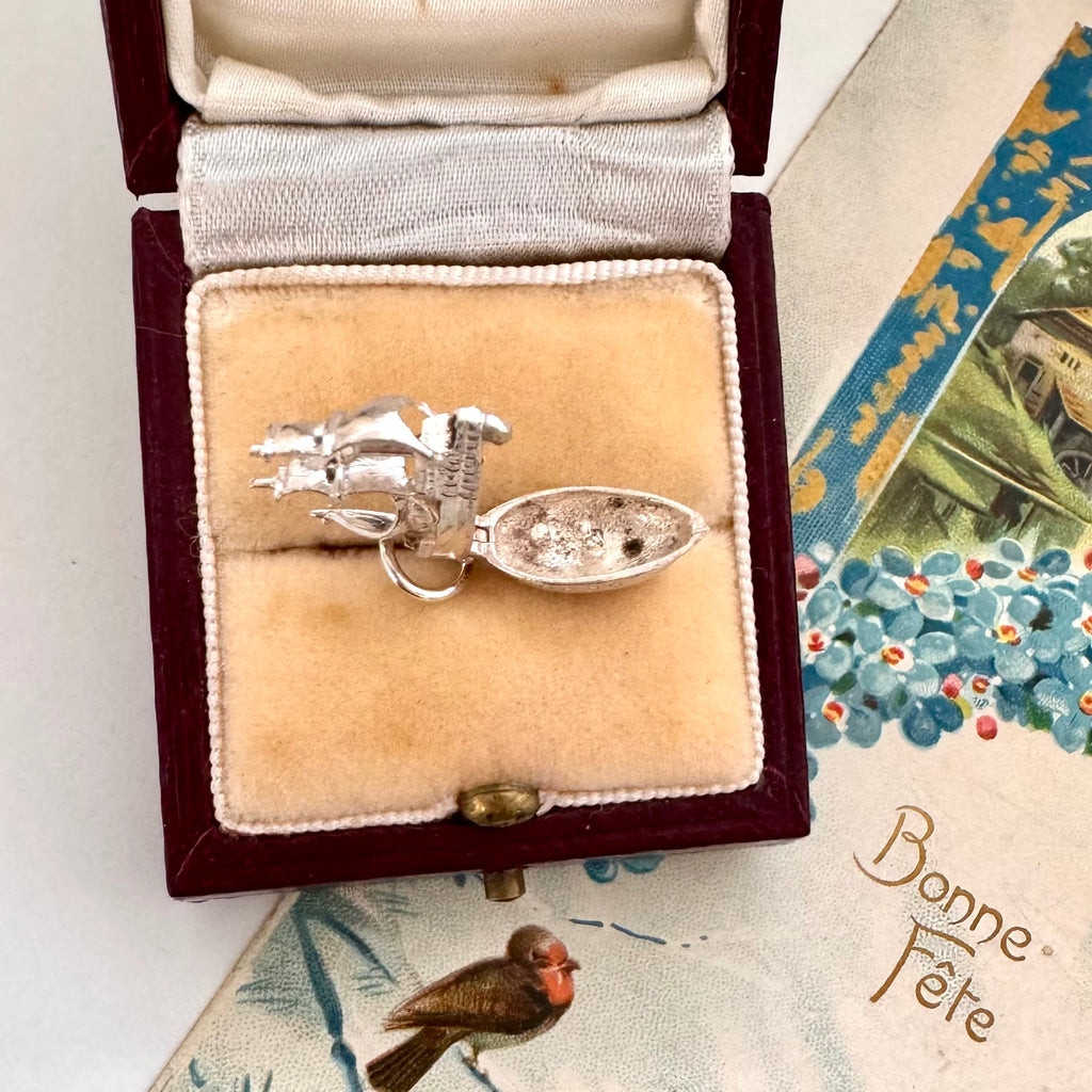 Vintage silver Mayflower ship charm in a jewelry box with a vintage card in the background