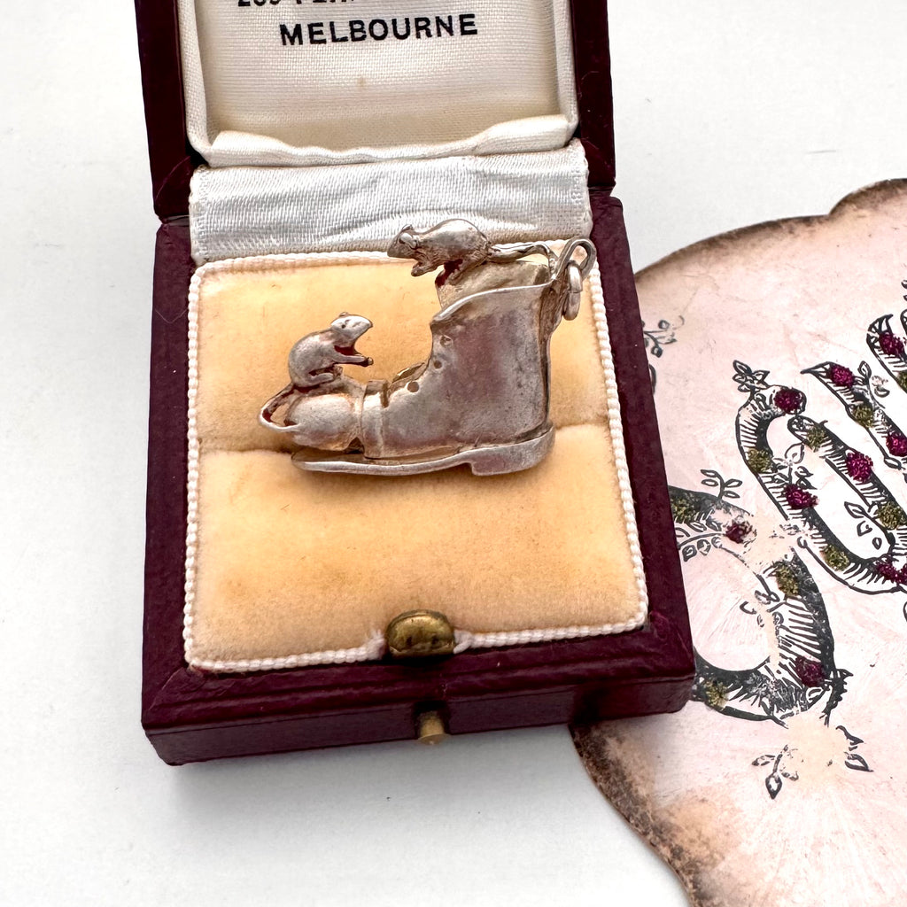 Vintage silver boot and mice charm on a jewellery box and with an old postcard in the background