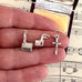 Three silver charms resembling buildings held between fingers on sheet music background
