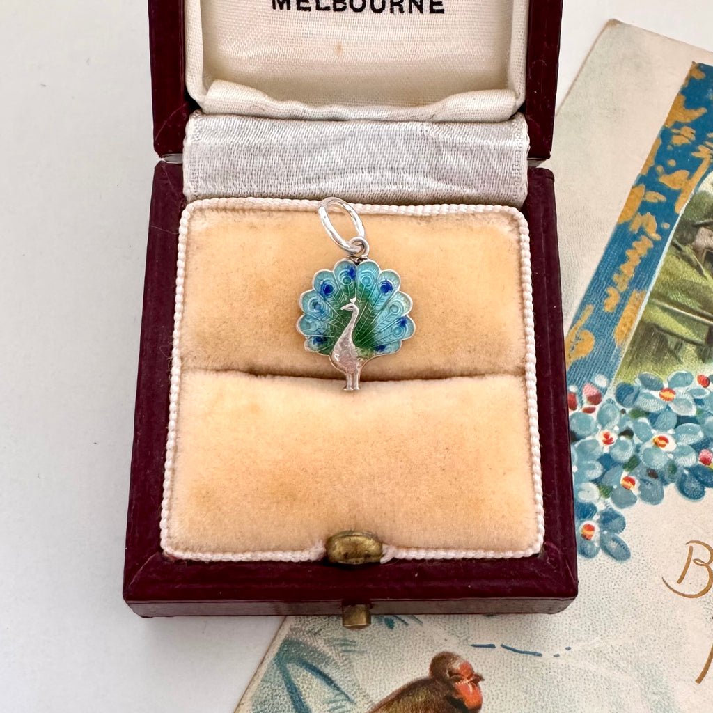 Vintage silver and enamel peacock charm in a jewelry box with 'Melbourne' branding