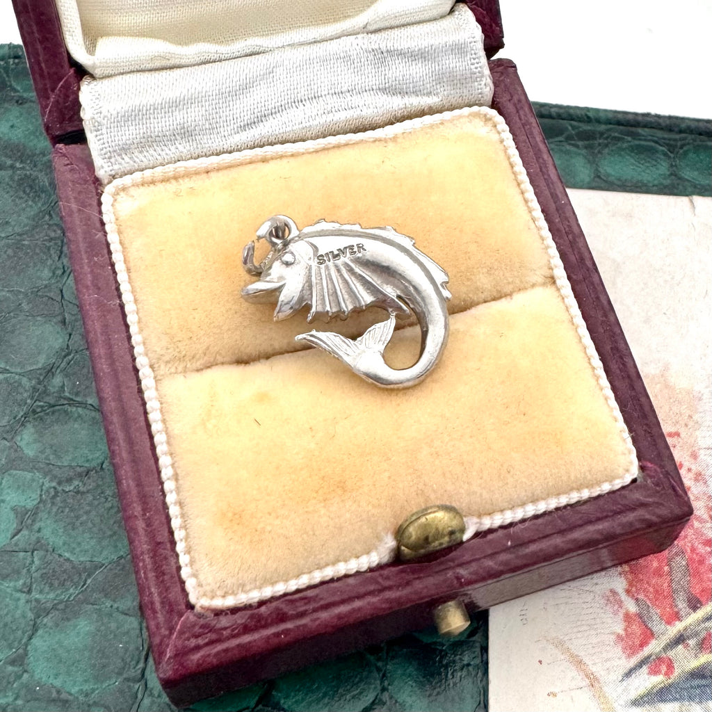 Vintage silver fish charm in a jewelry box with 'Silver' engraving.