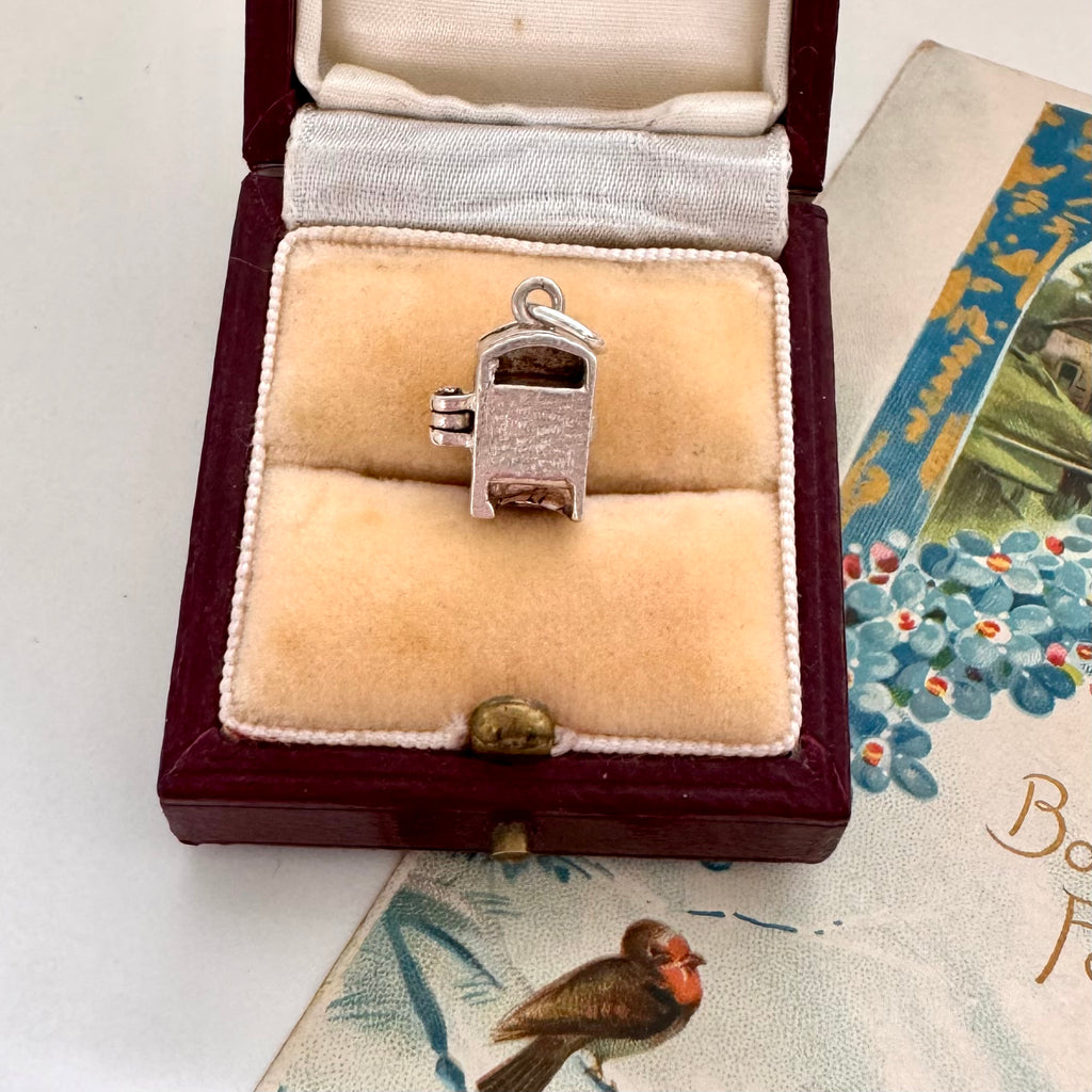 Vintage silver fridge charm in a jewelry box with vintage card in the background