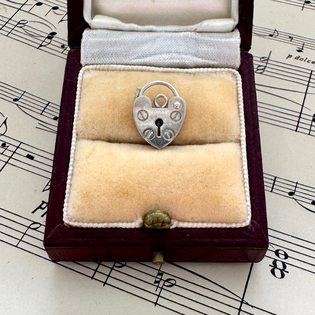 Silver heart-shaped lock pendant in a jewelry box on sheet music
