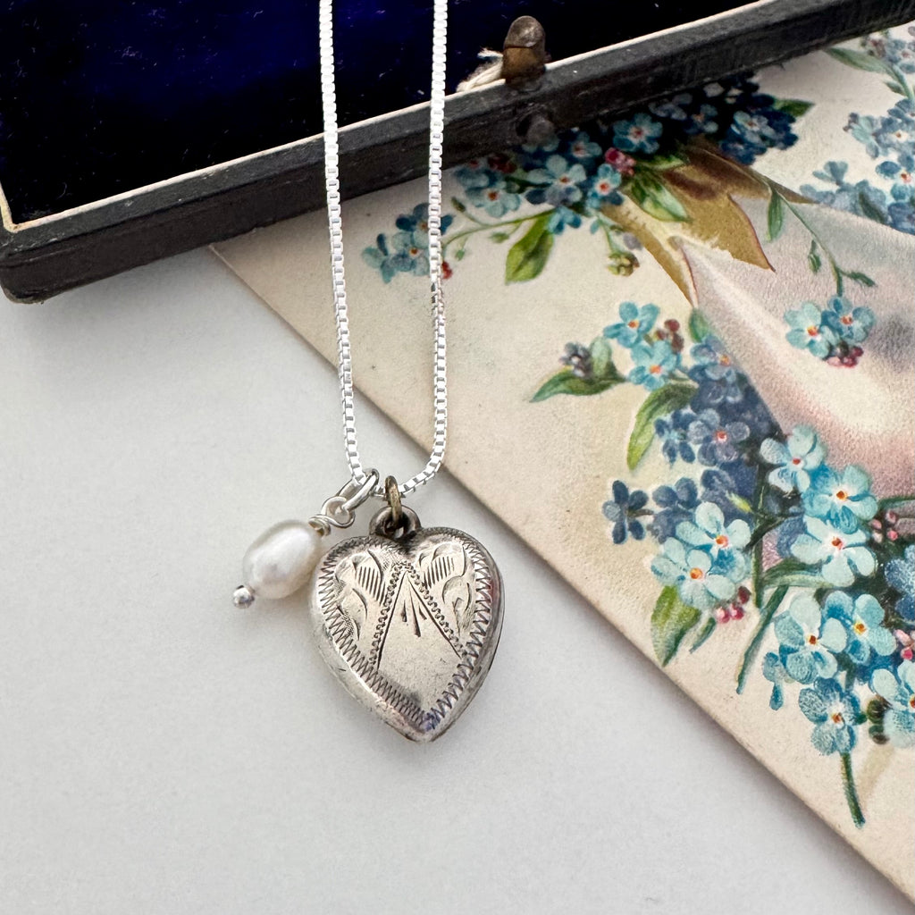 Vintage silver heart and pearl charms on a silver chain. The necklace is with a vintage postcard and vintage jewellery box