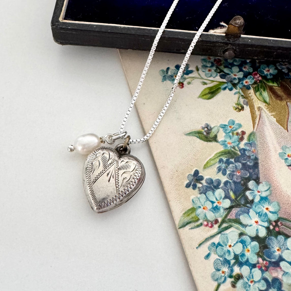 Vintage silver heart and pearl charms on a silver chain. The necklace is with a vintage postcard and vintage jewellery box