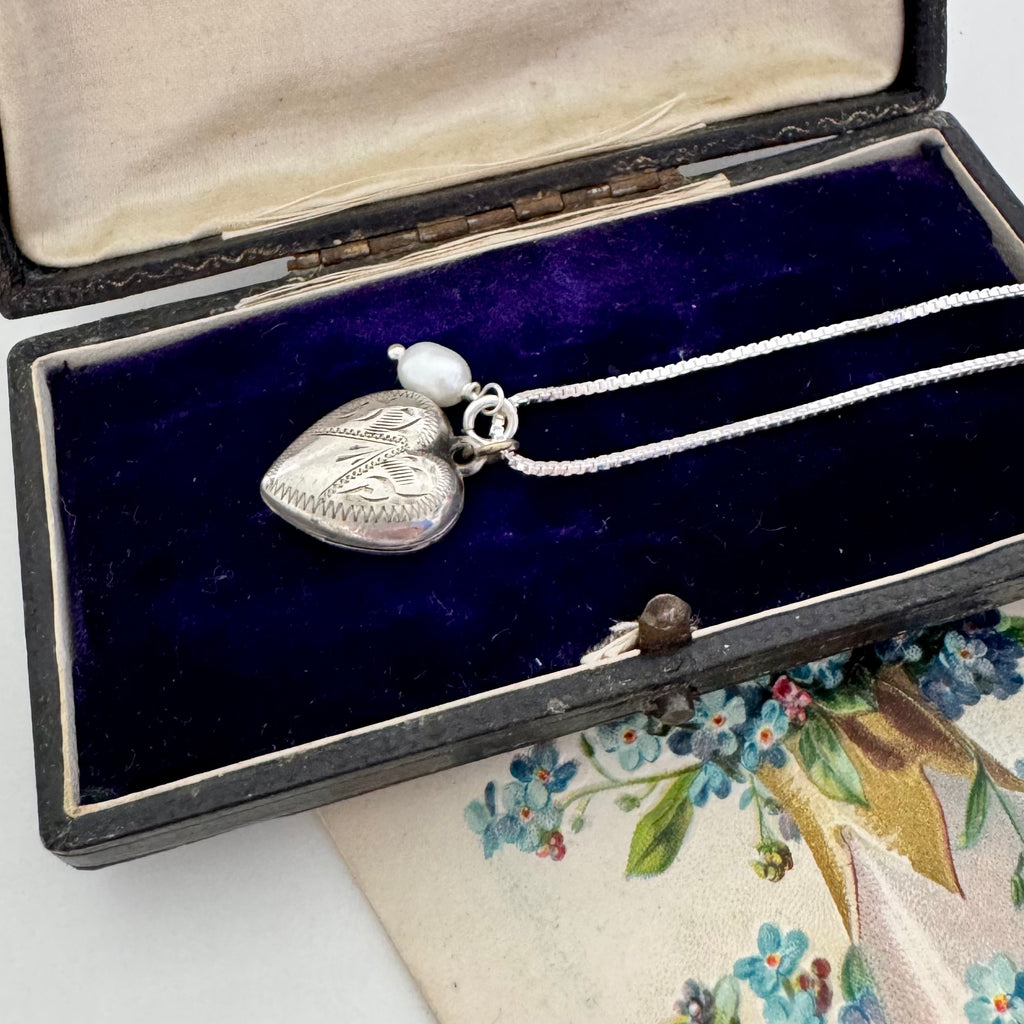 Vintage silver heart and pearl charms on a silver chain. The necklace is with a vintage postcard and vintage jewellery box
