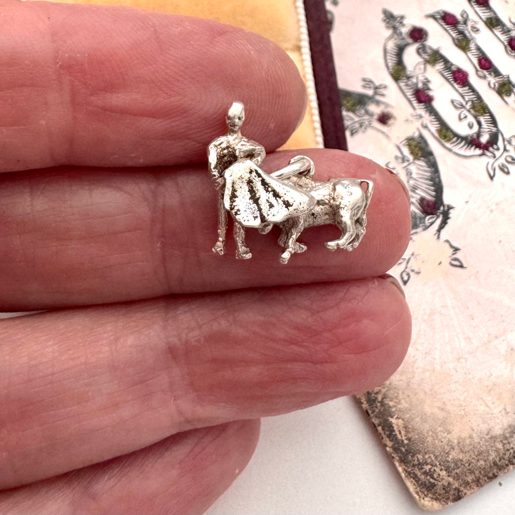 Vintage silver bullfighter charm in a woman's fingers