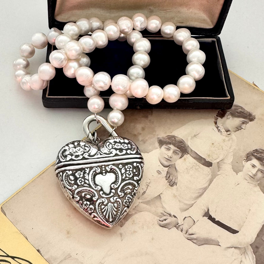 Pearl necklace with a silver heart-shaped locket on an old photograph