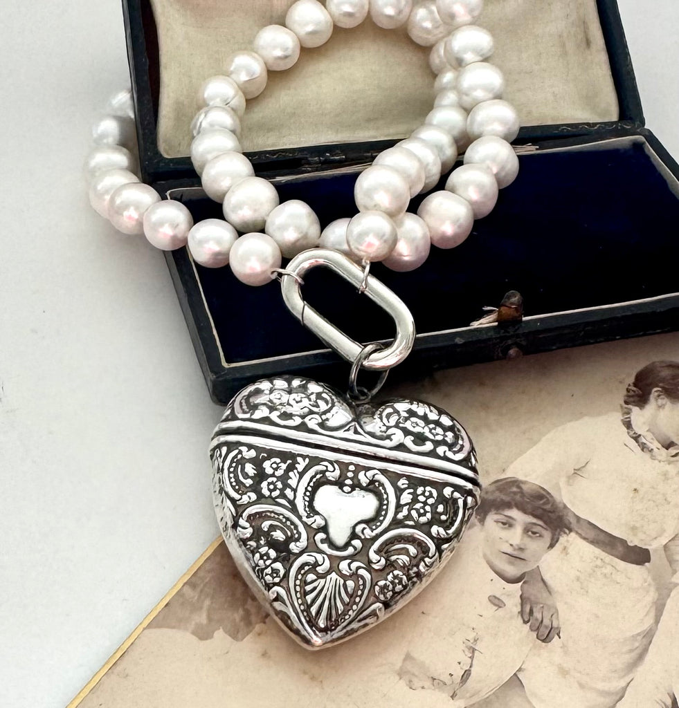 Pearl necklace with a silver heart-shaped locket on an old photograph